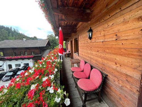 a porch with two chairs and flowers on a building at Appartements Zellner in Alpbach