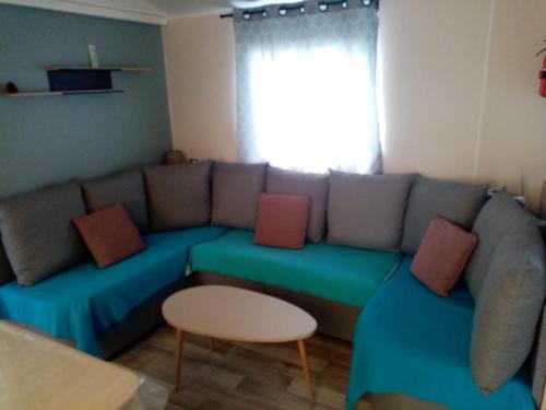 a living room with a blue couch with pillows at camping les charmettes in Les Mathes