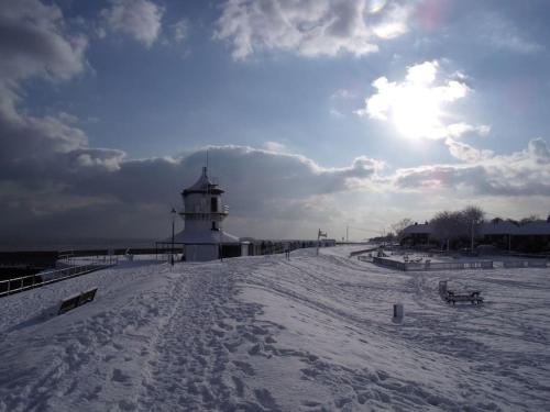 a lighthouse on a beach with snow on the ground at Tidal Walk Cottage by the Sea in Harwich