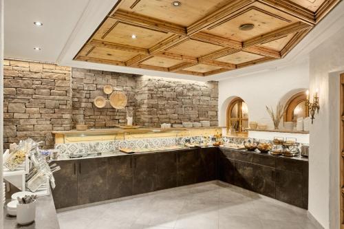 a large kitchen with a stone wall at Aktivhotel Feichtner Hof in Kaunertal