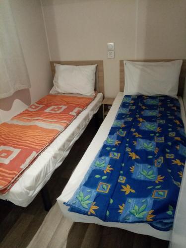 two beds sitting next to each other in a room at camping les charmettes in Les Mathes