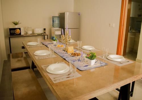 una larga mesa de madera con platos y comida. en Hype Holiday Homes en Karachi