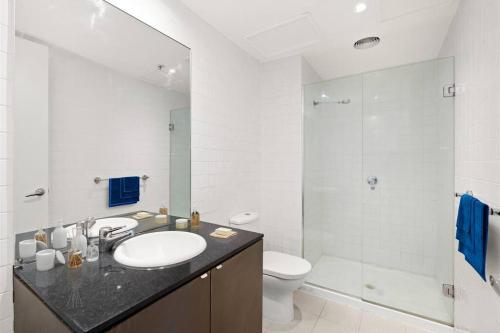a bathroom with a sink and a toilet and a mirror at Collins central 2-bd apartment with pre-reserve parking in Melbourne