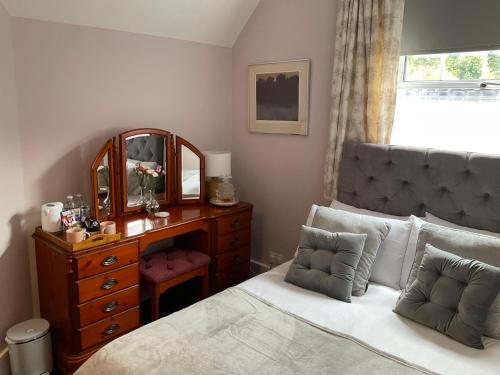 a bedroom with a bed and a dresser and a mirror at The Jolly Farmer in Bramley