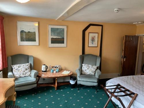 a hotel room with two chairs and a table and a bed at The Jolly Farmer in Bramley