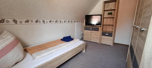 ein kleines Schlafzimmer mit einem Bett und einem TV in der Unterkunft Haus Dori in Krummhörn