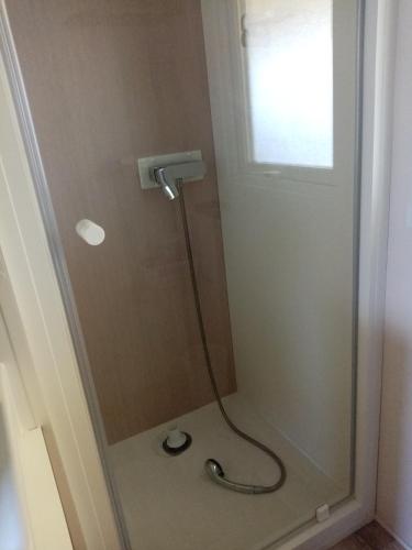 une douche avec une porte vitrée dans une salle de bain dans l'établissement camping les charmettes, aux Mathes