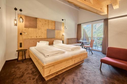 ein Schlafzimmer mit einem Bett, einem Tisch und einem Stuhl in der Unterkunft Aktivhotel Feichtner Hof in Kaunertal