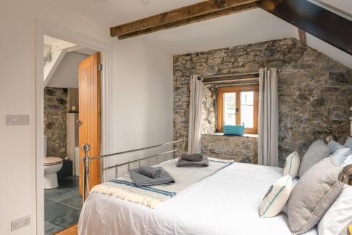 a bedroom with a large bed and a stone wall at Stunning Converted Granary in Heart of St Davids in St. Davids