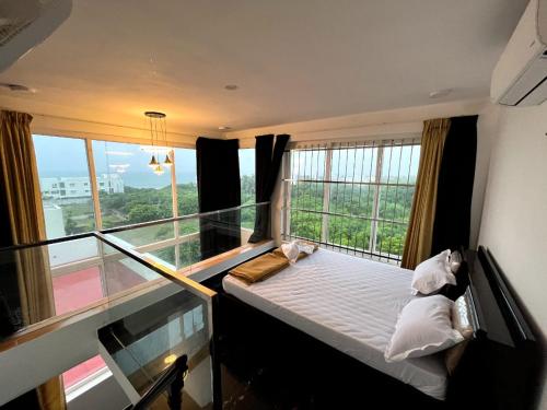 a room with a bed and a balcony with windows at Mer Vue Villa, Kovalam, ECR, Chennai in Chennai