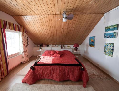 a bedroom with a red bed with a wooden ceiling at Moonlight House Large holiday villa with sauna and free parking in Rovaniemi