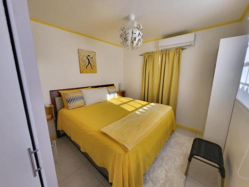 une chambre avec un lit jaune et un lustre dans l'établissement Villa Raven's Paradise (Rosado), à Willemstad