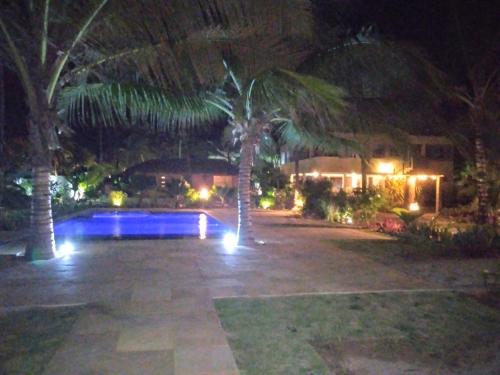 a backyard at night with a pool and palm trees at Vila Saguaro in Trairi