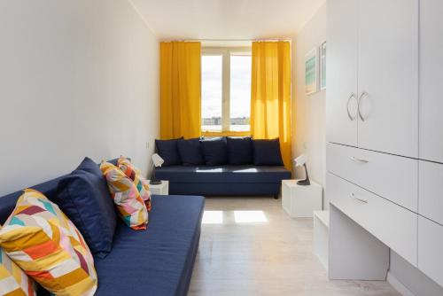 a living room with a blue couch and yellow curtains at Seaview Apartment Gdańsk Przymorze by Renters in Gdańsk