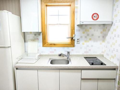 uma cozinha branca com um lavatório e uma janela em Prime Pension em Yangyang