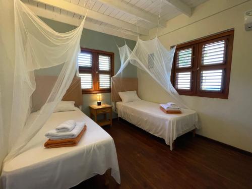 2 camas en una habitación con cortinas blancas en Westhill Bungalows & Diving, en Sabana Westpunt