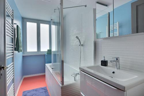 y baño blanco con lavabo y ducha. en "Urbaine Cosy" Elégance, confort et détente en Alsace "Les Péri-Urbaines", en Riedisheim