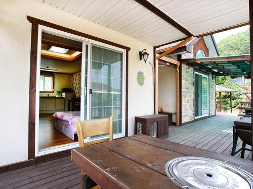 a porch with a wooden table and a bedroom at Prime Pension in Yangyang