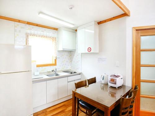 a kitchen with a table with chairs and a sink and a refrigerator at Prime Pension in Yangyang