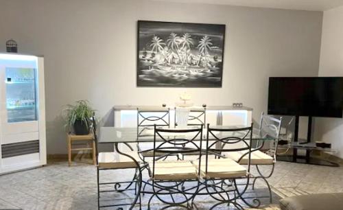 uma sala de estar com uma mesa e cadeiras e uma televisão em Villa de 3 chambres avec piscine privee jardin clos et wifi a Saint Froult a 1 km de la plageB em Saint-Froult