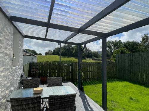 a pergola with a table and chairs on a patio at Cozy 2 bedroom cottage with log burner close to Loch Ken in New Galloway