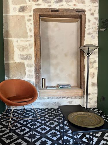 a room with a chair and a table and a window at LE CHAPITRE - Agréable maison de ville in Autun