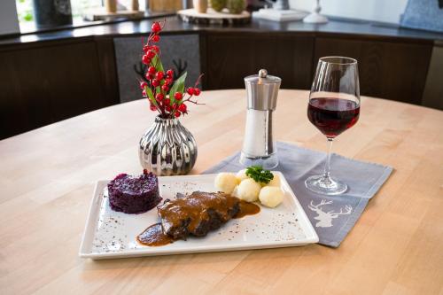 a plate of food and a glass of wine on a table at Hotel Neumaier in Xanten