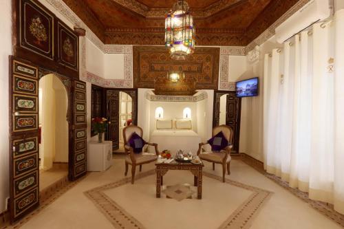 a living room with a table and chairs and a chandelier at Riad Palais Des Princesses & Spa in Marrakesh