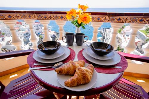 stół z 2 filiżankami kawy i rogalikami na balkonie w obiekcie FRONT LiNE OCEAN ViEW 2BeD Wi-Fi YOUR HOLiDAY HOME w mieście Puerto de Santiago