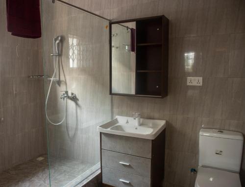 a bathroom with a sink and a shower with a mirror at Kislas Luxury Hotel in Pantang