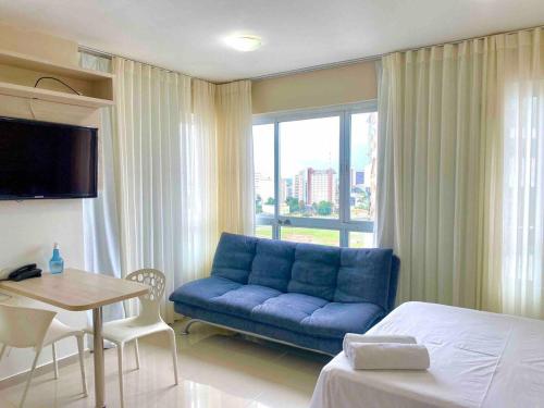 um quarto de hotel com um sofá azul e uma mesa em Saint Moritz no coração de Brasília em Brasília