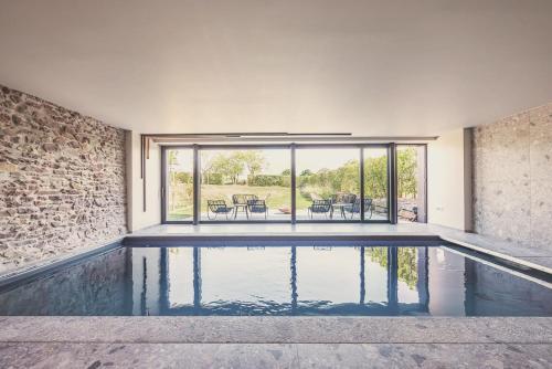 a swimming pool in a house with a brick wall at Domaine Sur Les Sarts in Ohey
