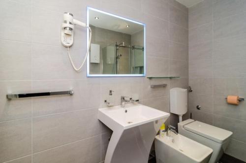 La salle de bains est pourvue d'un lavabo, de toilettes et d'un miroir. dans l'établissement Sunny Rooms, à Dubrovnik