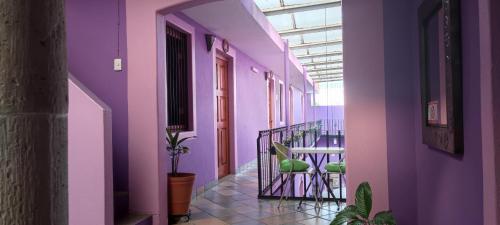 um corredor com paredes roxas, uma mesa e cadeiras em Posada don Matias em Oaxaca de Juárez