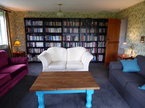 a living room with a white couch and a book shelf at High Ground Cottage, Eskdale in Eskdale