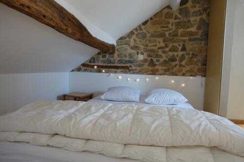 a bedroom with a white bed with a stone wall at « Le LoMa » Ancienne fermette in Hotton