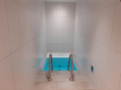 uma casa de banho com uma banheira azul num quarto com azulejos brancos em Appartement Wettersteinblick em Seefeld no Tirol