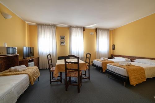 una camera d'albergo con tre letti e un tavolo con sedie di Hotel Siros a Verona