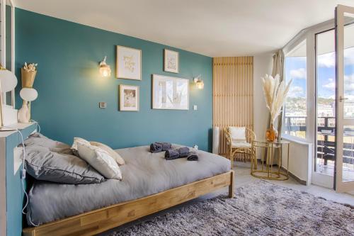 1 dormitorio con pared azul, cama y mesa en LA REV'RIE - vue sur mer avec balcon en Deauville