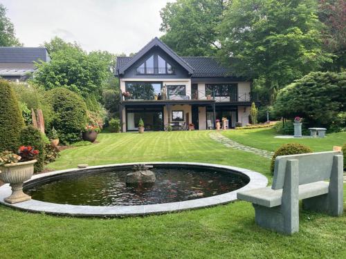 ein Haus mit einem Teich und einer Bank im Hof in der Unterkunft Ferien im Königshaus in Möhnesee