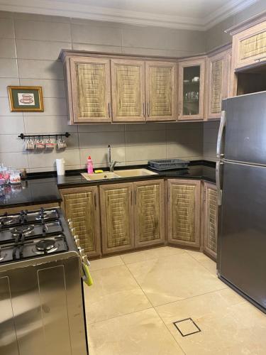 a kitchen with wooden cabinets and a stainless steel refrigerator at A Luxury 2 Bedroom With a perfect location in Sweifiyeh in Amman