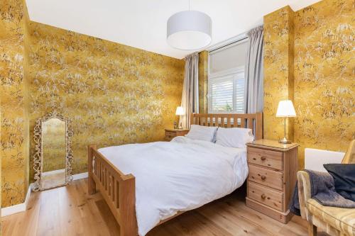 Glasgow Harbour Clyde Waterfront Apartment في غلاسكو: غرفة نوم بسرير كبير وورق جدران اصفر