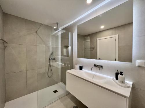 a bathroom with a shower and a sink and a mirror at Quarteira Stylish by Homing in Quarteira