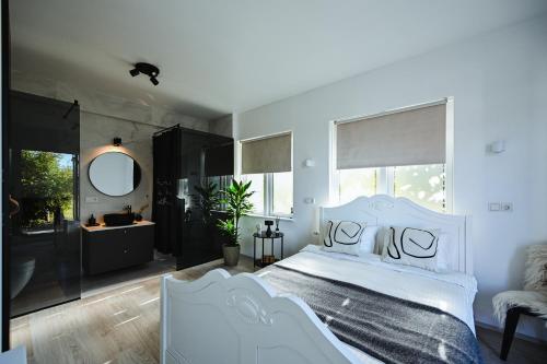 a bedroom with a white bed and a mirror at ÁLka - Cozy Room by the Sea With Private Hot Tub in Njarðvík