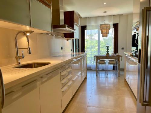 a kitchen with white cabinets and a sink and a table at Doncella Beach , apartamento con vistas al mar in Estepona