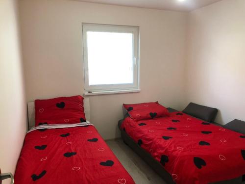 1 dormitorio con 2 camas con sábanas rojas y ventana en ubytovanie u MITIho en Szalóc