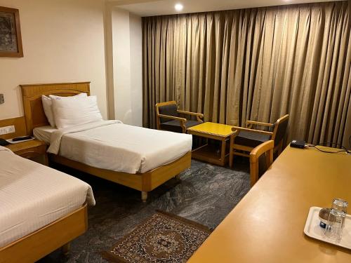 a hotel room with two beds and a table and chairs at ASR Guesthouse in Tirupati