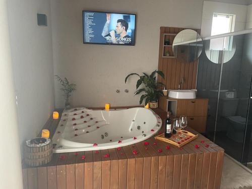 a bath tub in a bathroom with a tv on the wall at Império Cabanas in Urubici