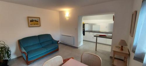 a living room with a blue couch and a kitchen at T2 indépendant dans maison Tout confort in Die