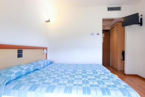 a bed in a room with a blue comforter at Albergo Ristorante La Greppia in Montedivalli Chiesa